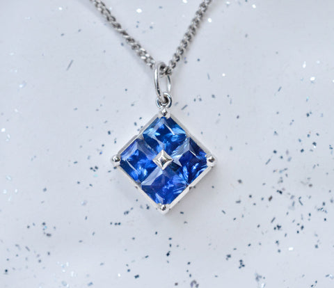 18K white gold square pendant with four princess cut Ceylon blue sapphires
