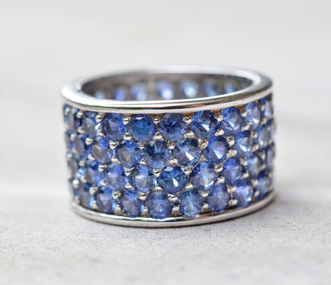 18K white gold ring with a thick band studded with four rows of blue sapphires