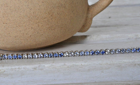 Blue and white sapphire bracelet with single line of gemstones in 18K white gold