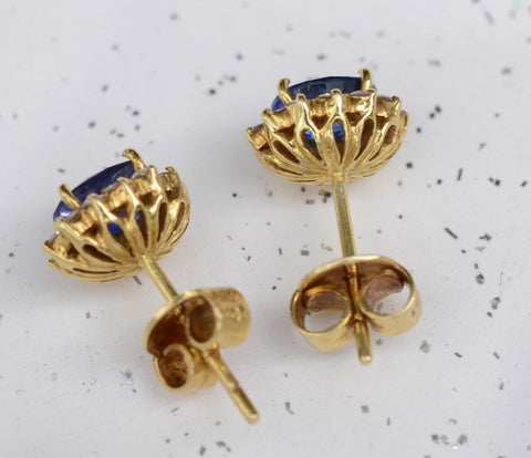 Natural Ceylon Blue Sapphire center piece earrings surrounded by 24 diamonds set in 18K carat yellow gold available at Elizabeth Jewellers in Sri Lanka